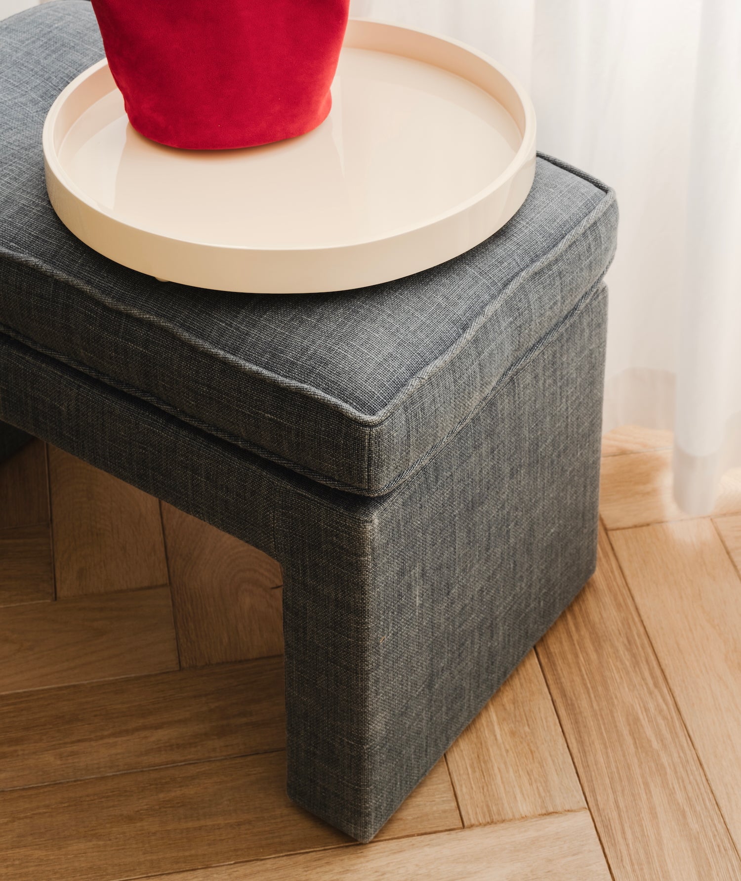Blue ottoman with a De Rosee Sa lacquered tray on a wooden floor.