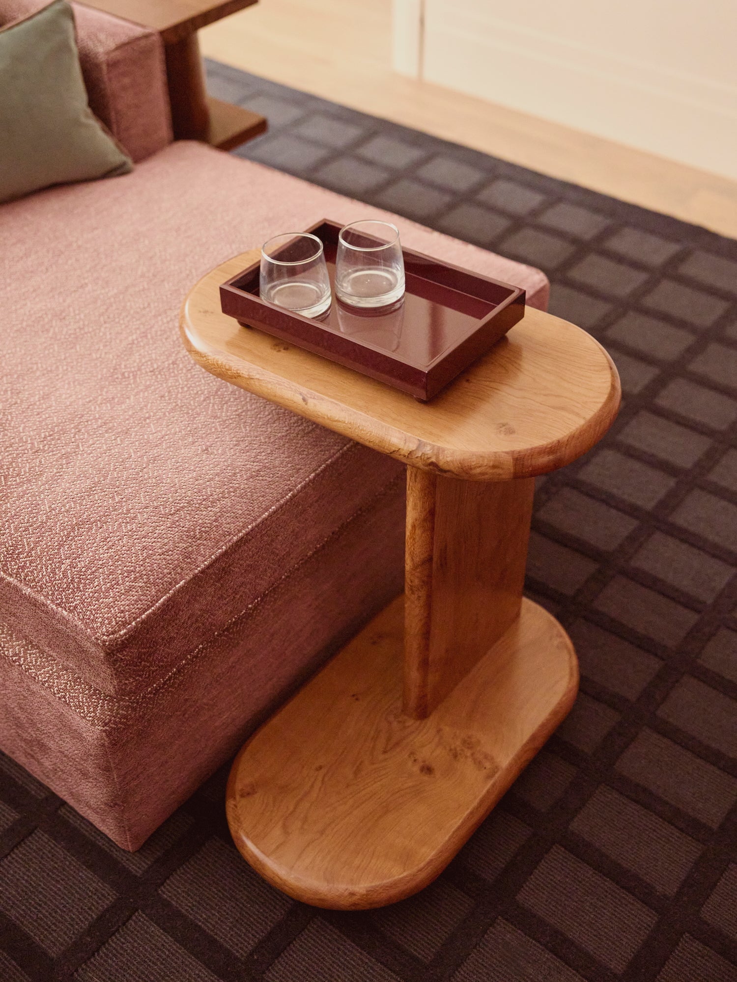 Wooden side table in oak burr with a high gloss lacquered tray holding two glasses.
